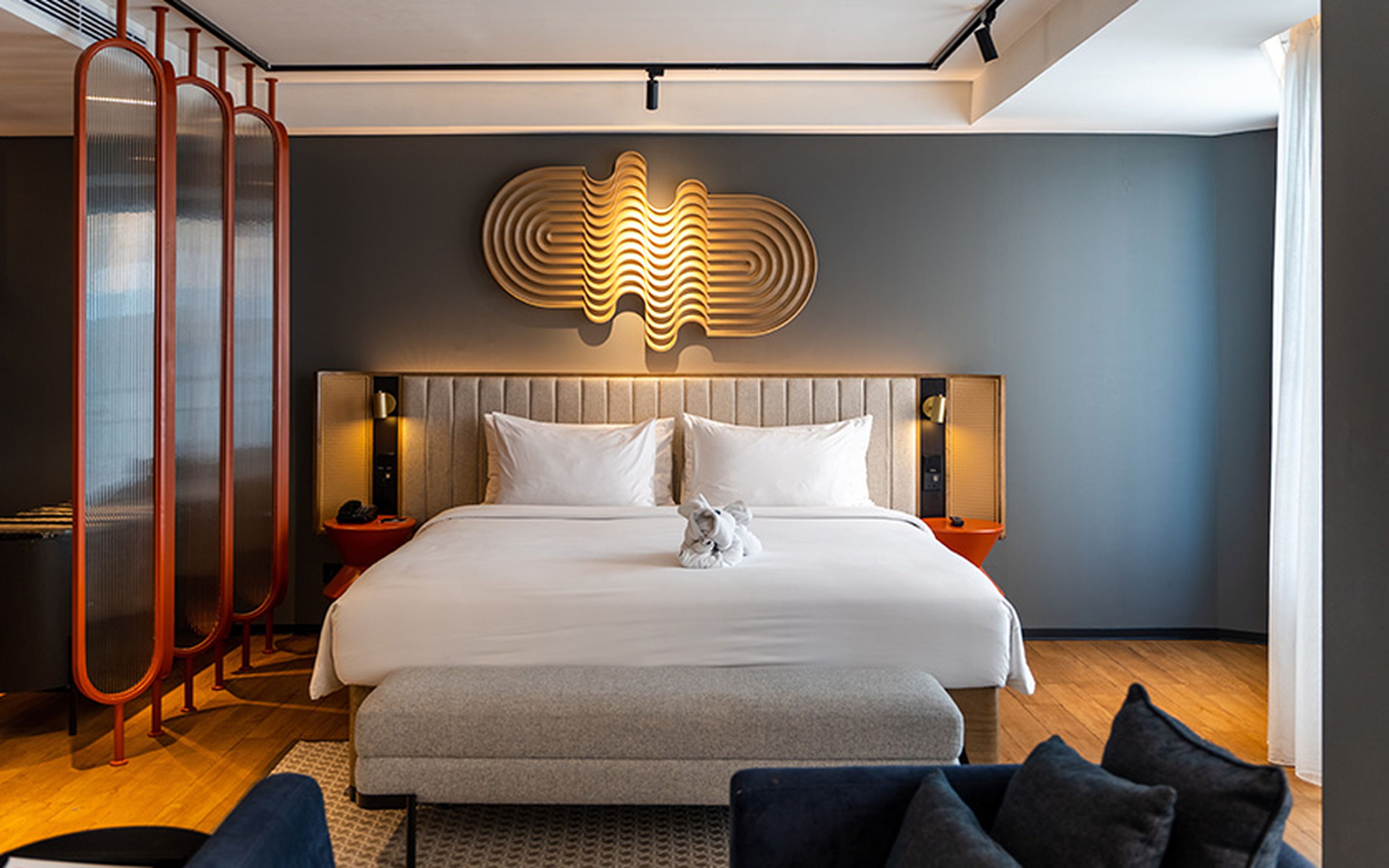 Luxury hotel room with minimal furnishings, featuring a neatly made bed, soft lighting and a clean, uncluttered design.