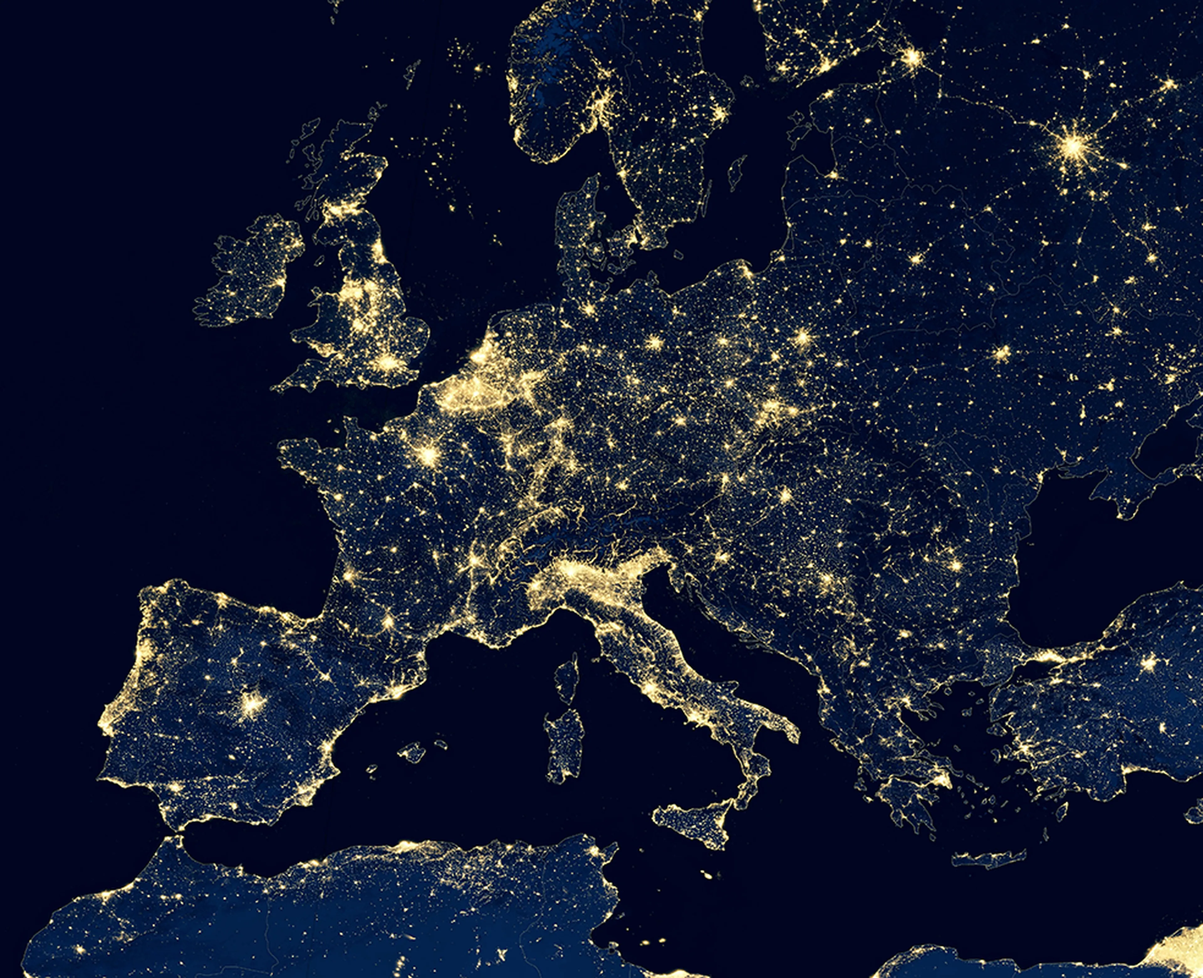 Satellite view of Europe at night, showing densely populated areas illuminated with bright city lights against a dark landscape.